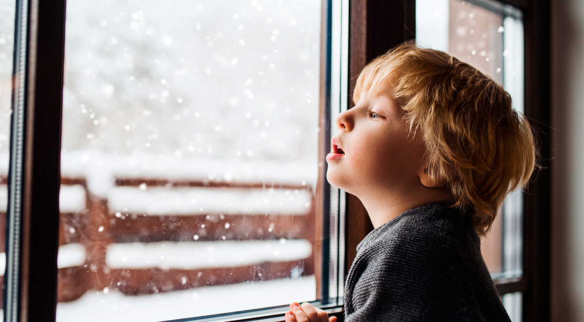 Lapsi katsoo ikkunasta talvimaisemaa.