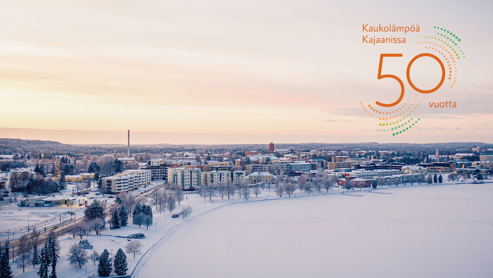 Ilmakuva Kajaanin kaupungista talvella Loiste Lämpö 50 v. logon kanssa